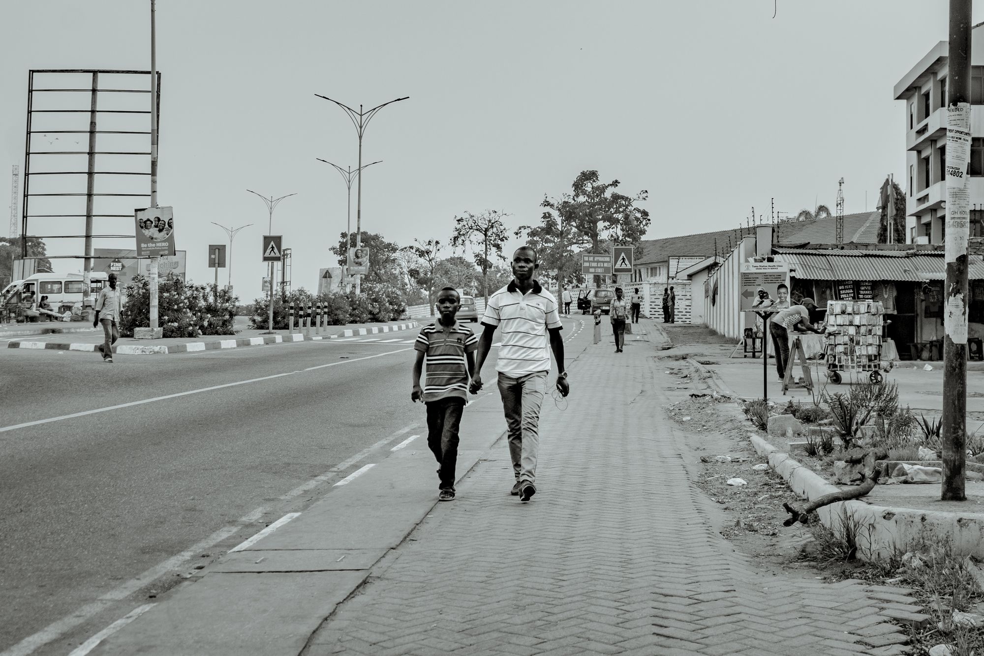 An adult man and a young man walking hand in hand in Accra: A photo by David Elikwu